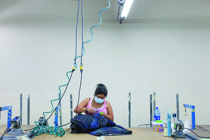 A worker frays a pair of jeans at Koos Manufacturing in Los Angeles.