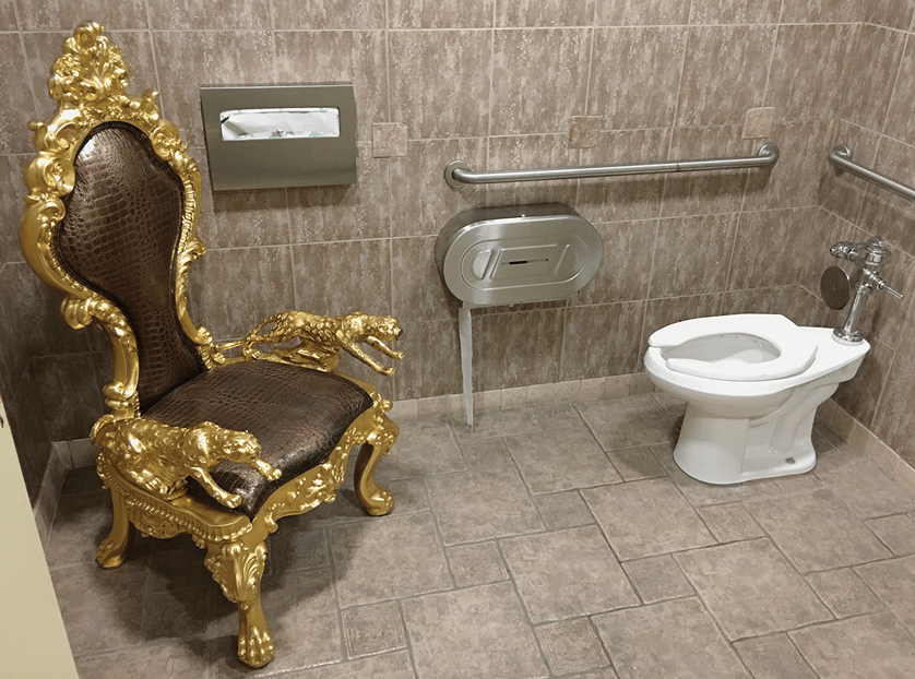 An elaborate throne sits inside a public restroom.