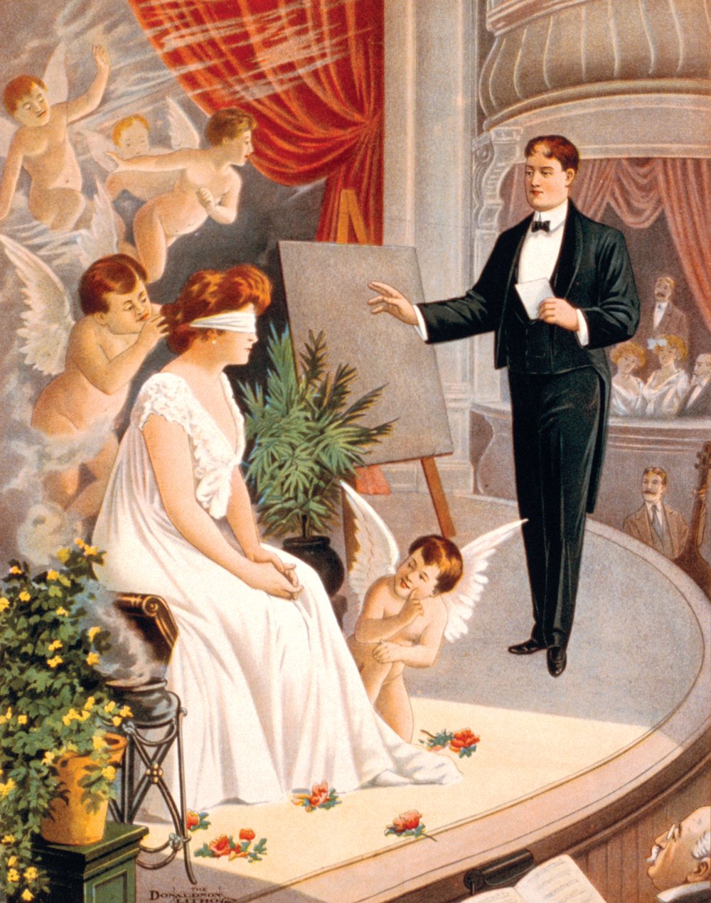 A hypnotist waves his hands as cupids surround a blindfolded woman in white on a theater stage.