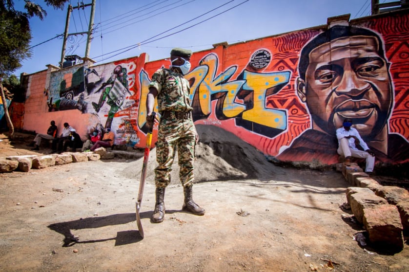 A National Youth Service officer is seen standing close by a painting mural representing police brutality.