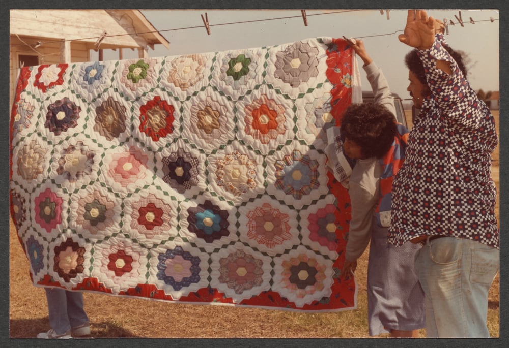 Men hanging a quilt from a clothesline.