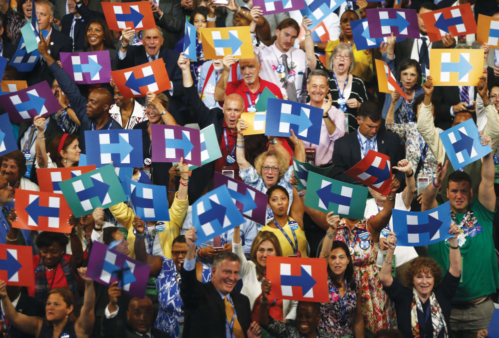 Attendees of a 2016 Hillary Clinton rally hold up almost identical signs.