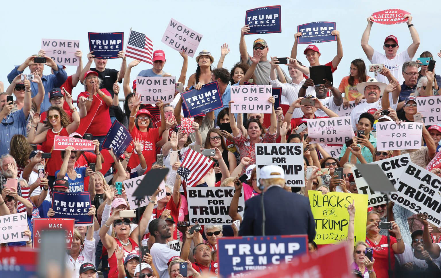 Trump rally attendees hold up signs that read “Women for Trump” and “Blacks for Trump.”