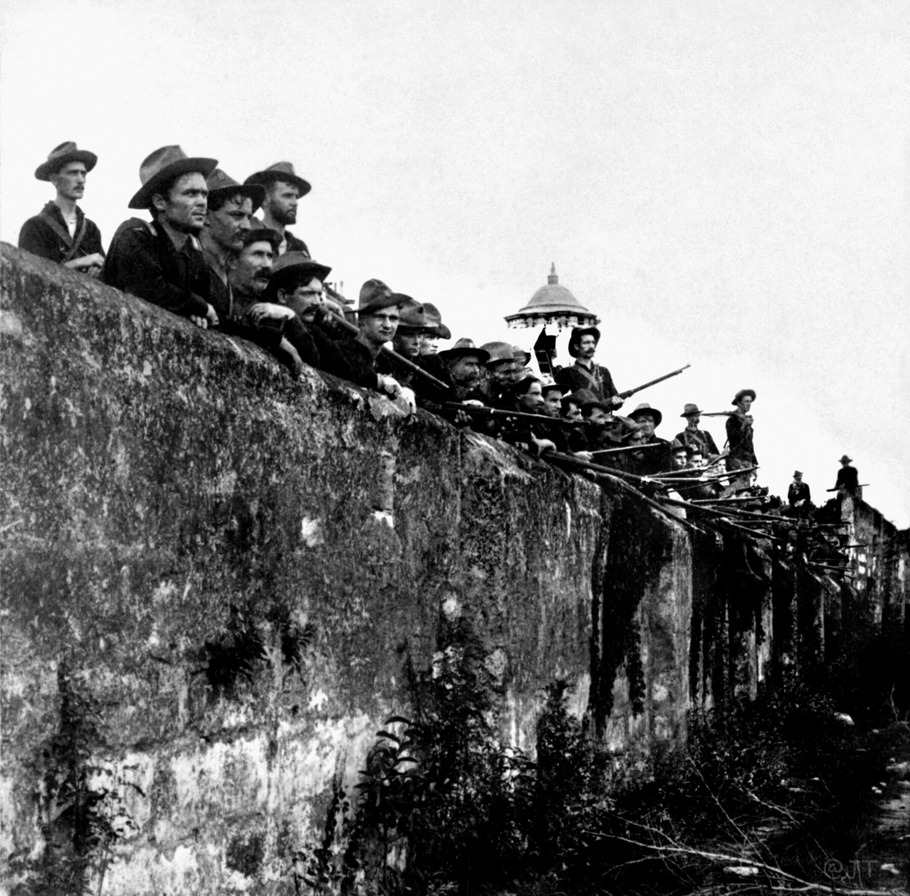 Soldiers stand behind a fortification.