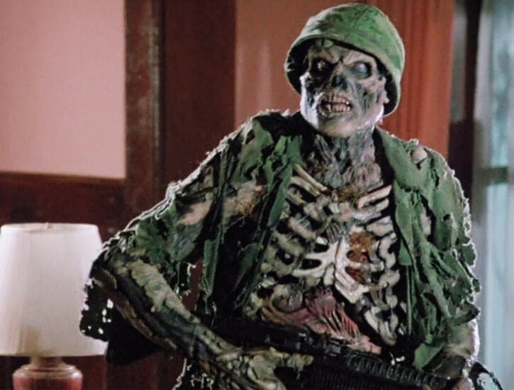 A zombie in army fatigues holds a gun.