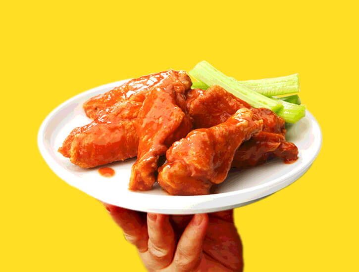 A small plate of chicken wings against a yellow backdrop.