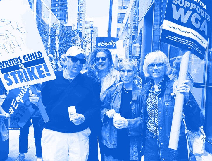 Four WGA picketers pose with signs on a street.