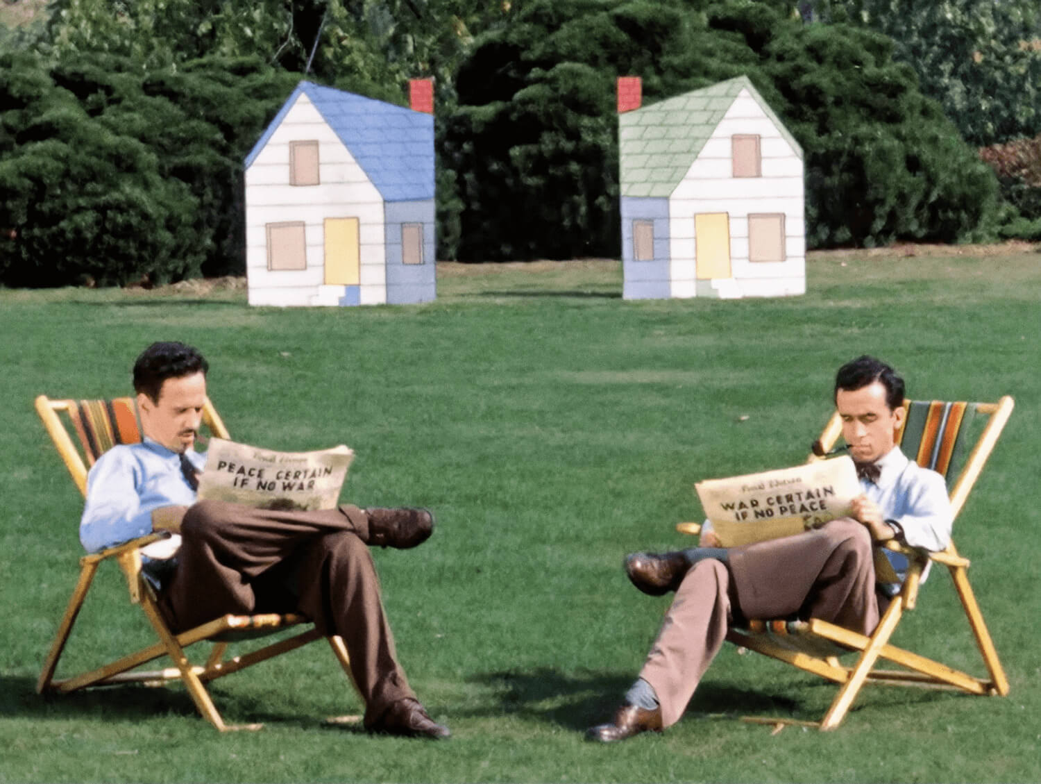 A still from the 1952 film Neighbors features two white men sitting across from each other on a lawn, reading newspapers.