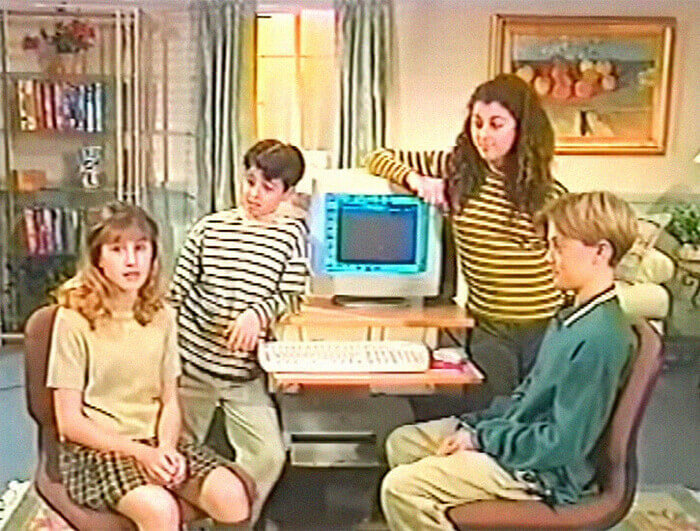 Several young people sit around a desktop computer.