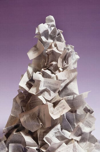 A mountainous heap of crumpled papers stands before a purple ombre backdrop.
