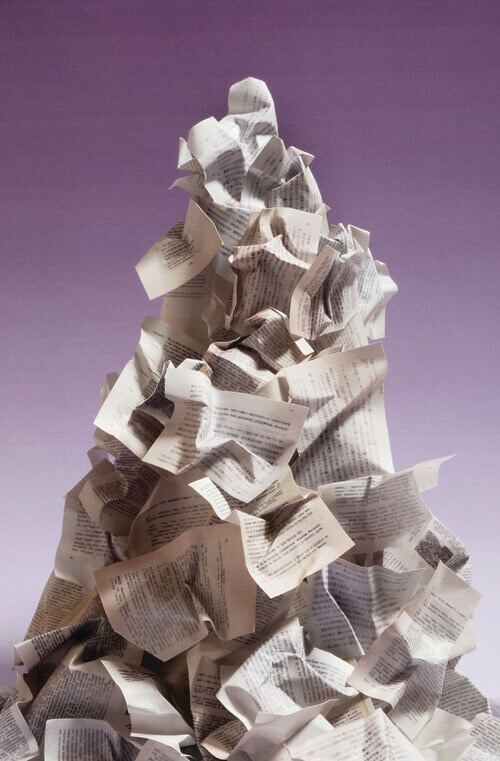 A mountainous heap of crumpled papers stands before a purple ombre backdrop.