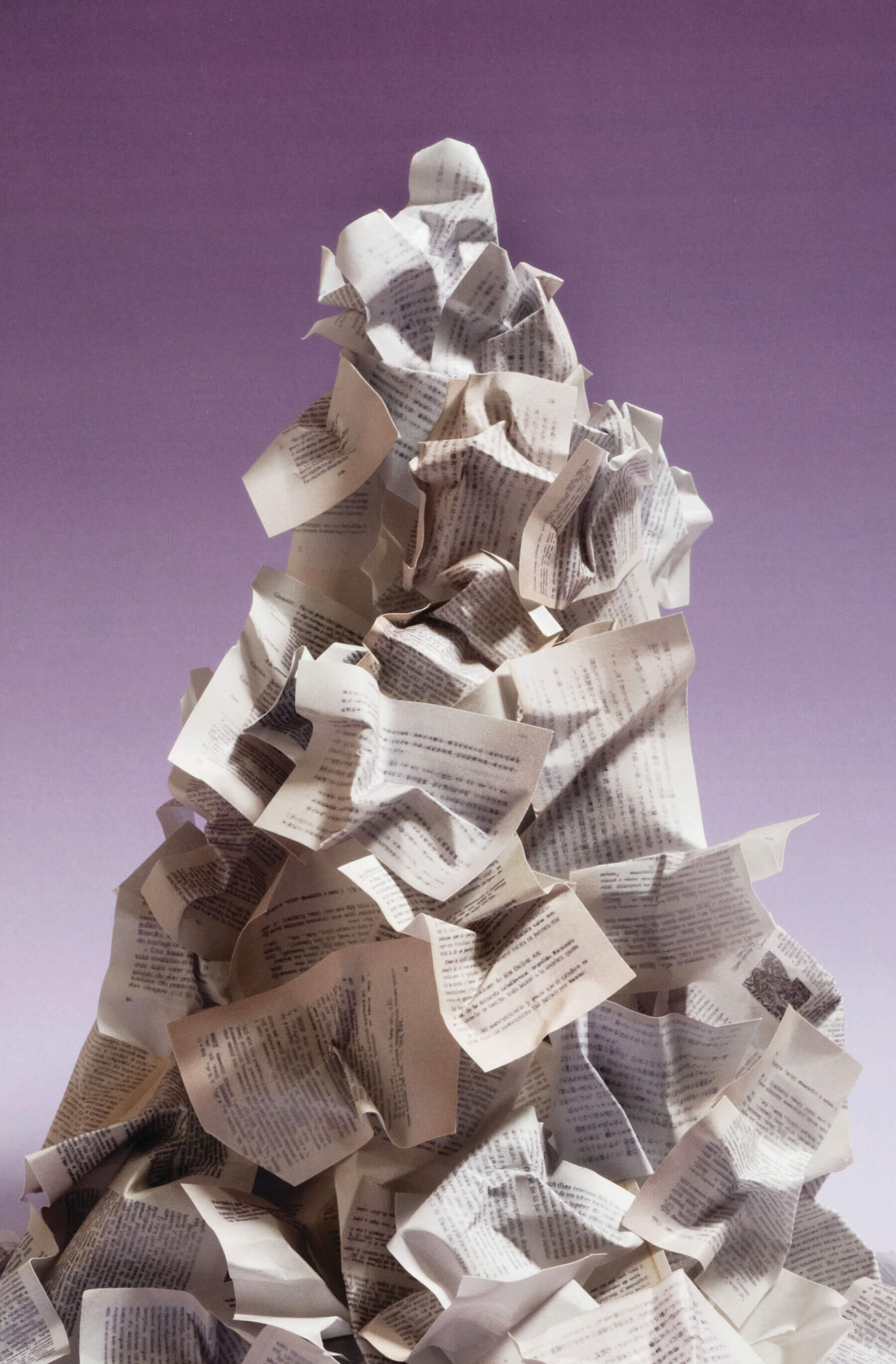 A mountainous heap of crumpled papers stands before a purple ombre backdrop.