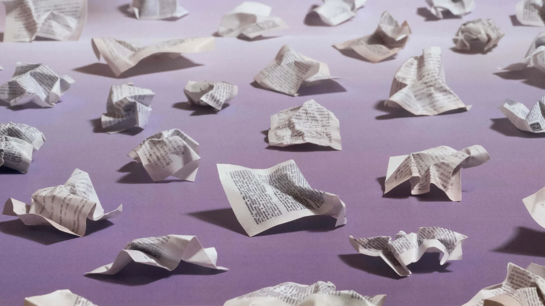 An image of crumpled papers scattered across a purple surface.