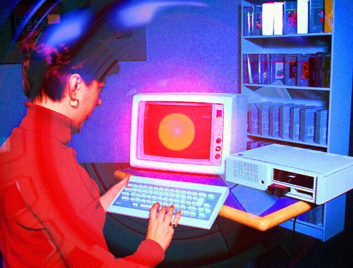 A woman uses an old-fashioned desktop computer. On the screen, the computer from the film "2001: A Space Odyssey" appears.