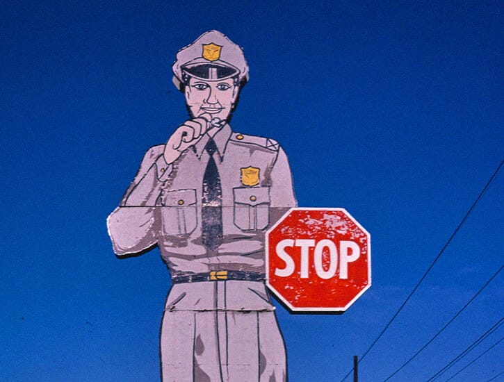 A large billboard in the shape of a police officer holding a stop sign.