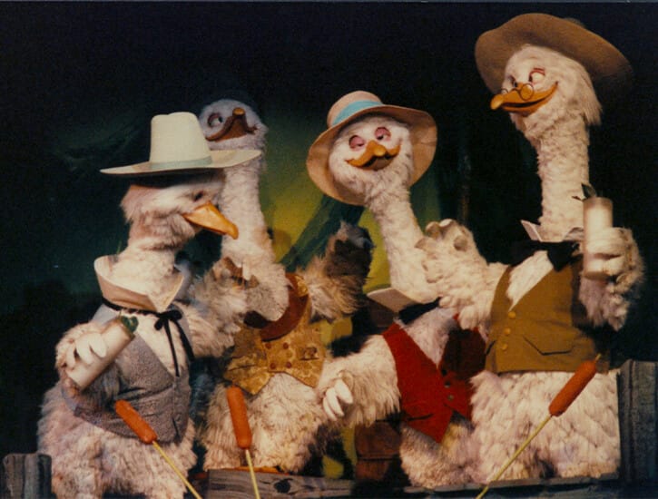 A group of four animatronic geeze in human clothes.