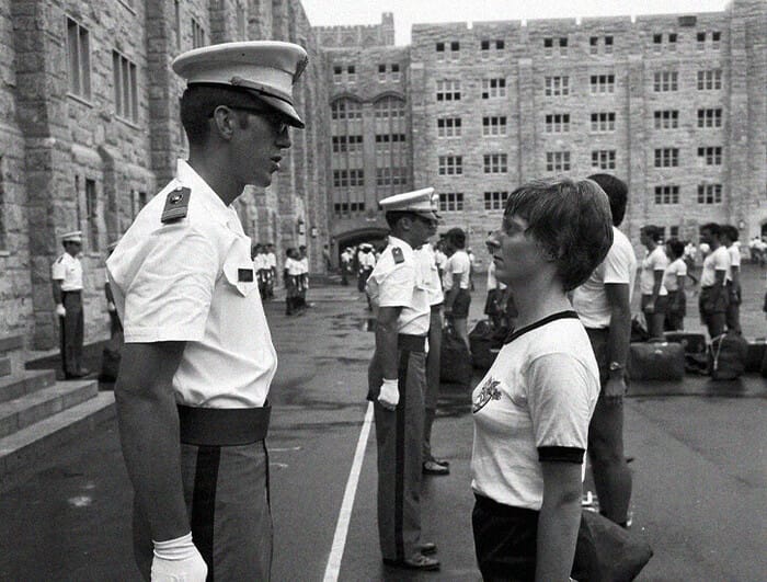 A male military officer stares down a young female cadet on the grounds of West Point.