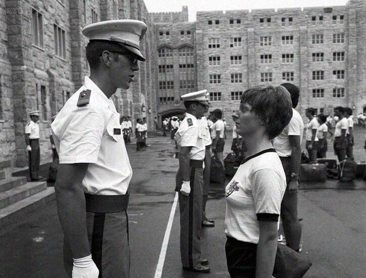 A male military officer stares down a young female cadet on the grounds of West Point.