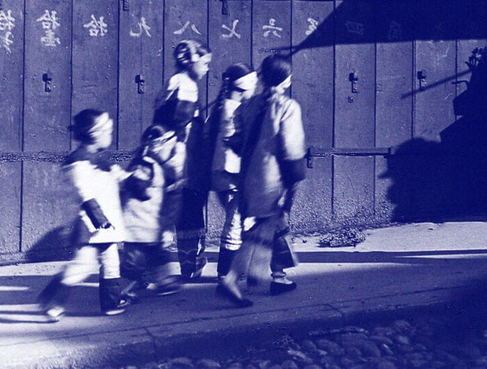 Five girls in holiday finery walk down a street in San Francisco's Chinatown.
