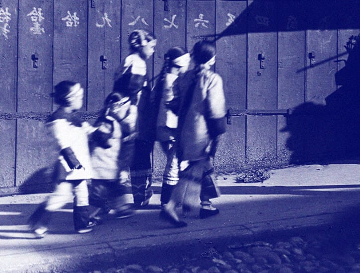 Five girls in holiday finery walk down a street in San Francisco's Chinatown.